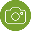 White camera icon centered within a green circle on a white background.